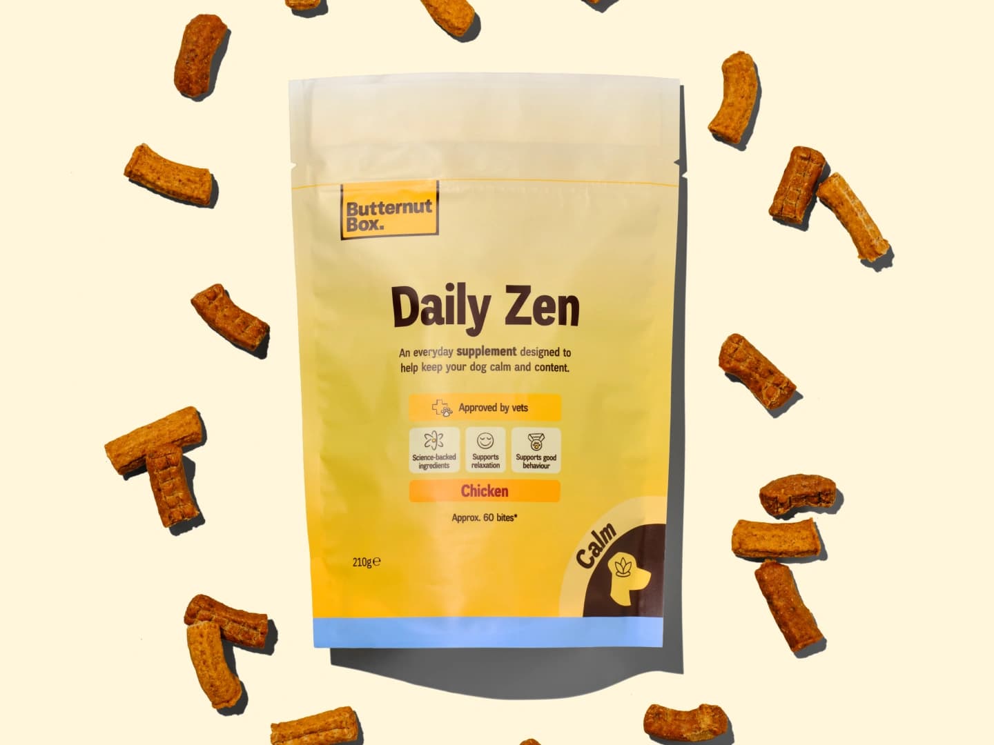 Butternut Box Daily Zen dog supplement package surrounded by chicken-flavored treats on a light background.